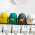 A whimsical, adorable resin duck keycap displayed prominently, showcasing its vibrant colors and smooth artisan finish. This charming duck keycap design.