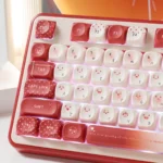 Close-up of playful red emoticon PBT keycaps in MOA profile, featuring charming heart accents and kaomoji designs, showcasing their cute details.