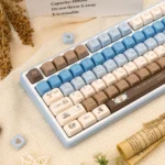 Close-up of premium PBT Gourmet Sea Salt keycaps, showcasing crisp dye-sub legends. The warm brown, creamy white, and subtle grey palette evokes.