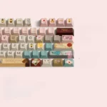 Grand Budapest PBT keycaps set, showcasing intricate pastel art deco designs and whimsical Wes Anderson aesthetic from various angles.
