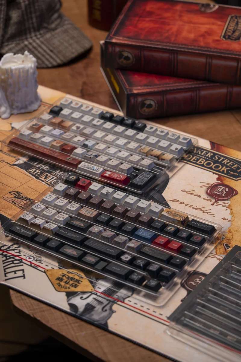 Sherlock Holmes PBT Dye-Sub keycaps set, shown from multiple angles, reveal their vintage detective aesthetic and intricate cipher book designs.