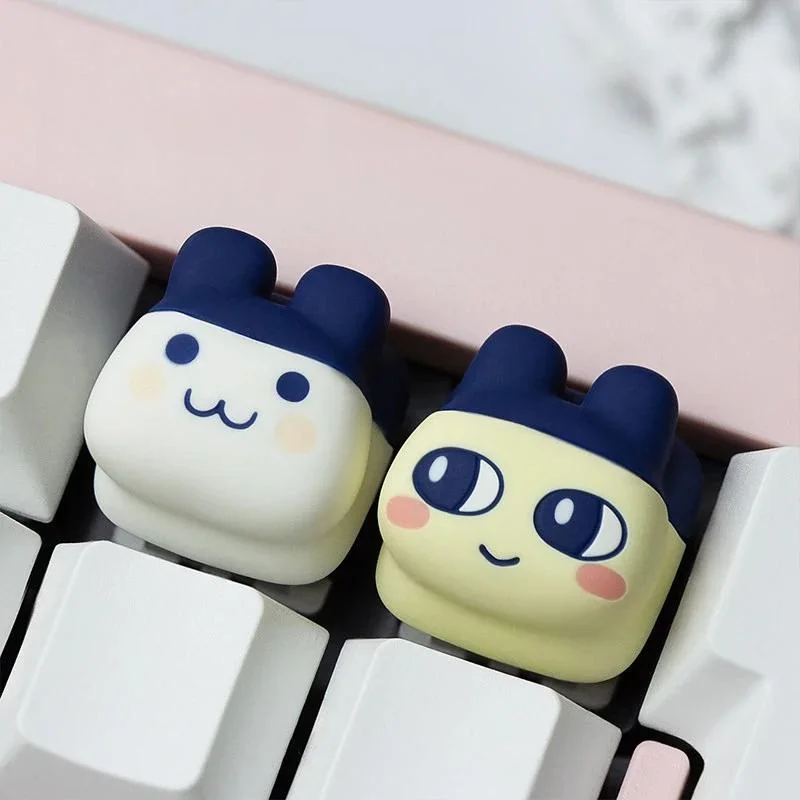 Product gallery of playful pixel Tamagotchi artisan keycaps from different angles, showcasing vibrant colors and nostalgic keyboard charm.