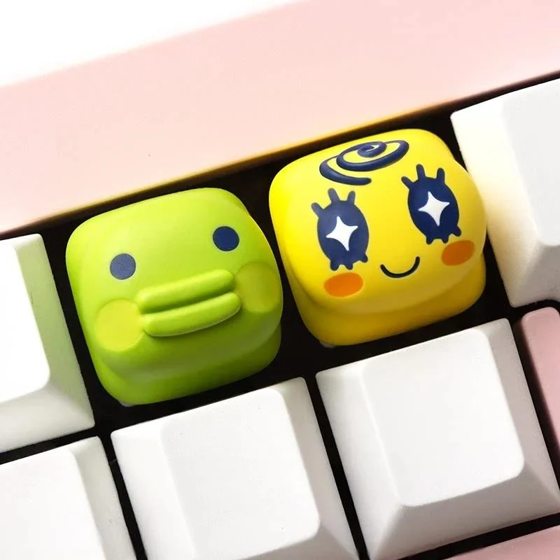 A collection of charming, pixel Tamagotchi keycaps displayed from various angles, highlighting their vibrant colors.