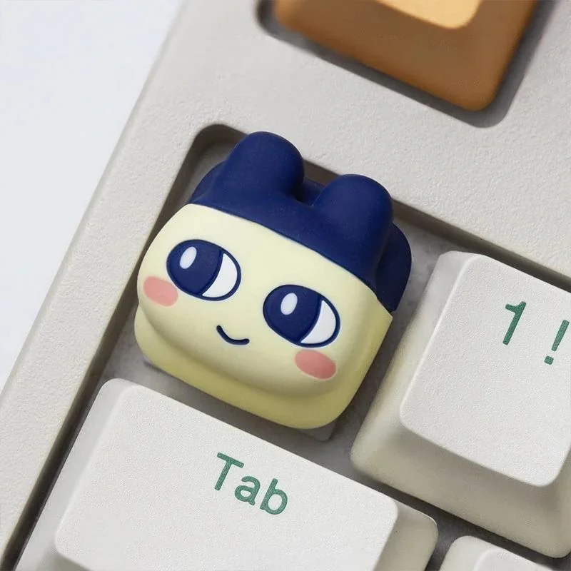 Vibrant gallery of Tamagotchi artisan keycaps, showcasing charming pixel pet designs from various angles on a keyboard.