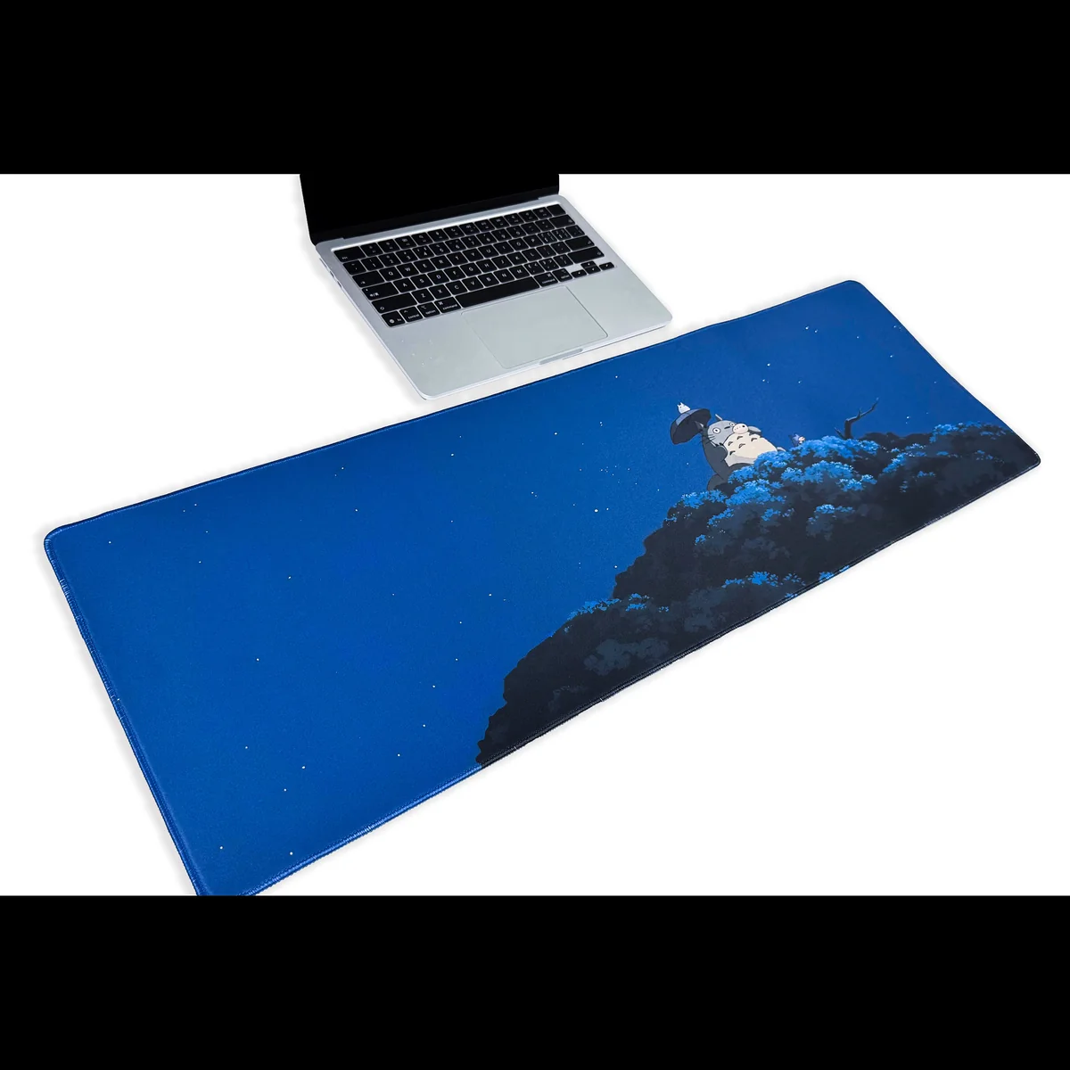 Overhead shot of the enchanting Totoro desk mat, showcasing whimsical Studio Ghibli characters in a serene forest, a spacious and playful desk access.