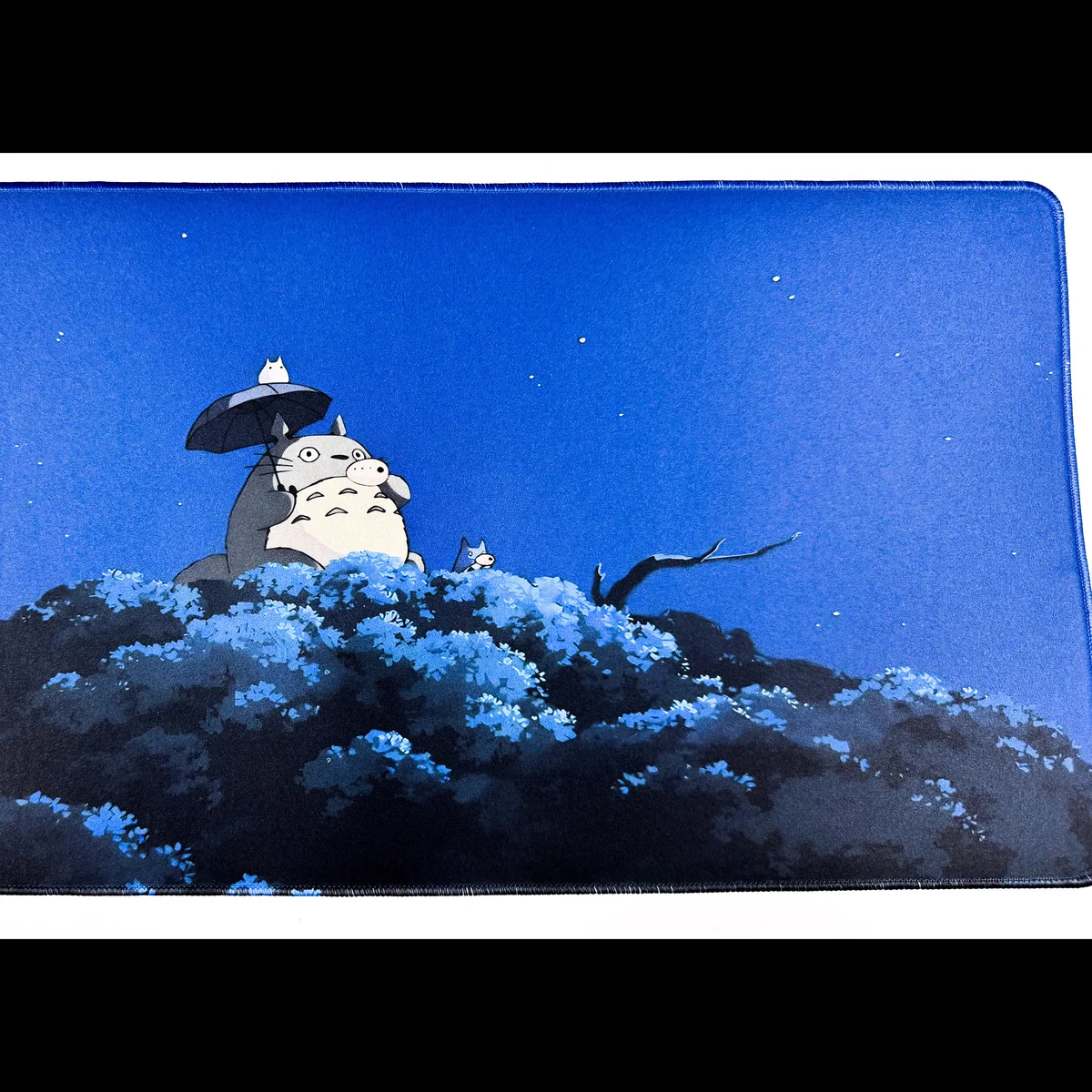 Close-up of the enchanting Totoro Desk Mat, showcasing whimsical Totoro characters frolicking in a serene forest scene, adding playful charm to your workplace.