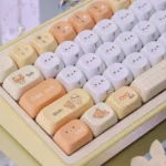 A playful gallery showcasing the adorable Rilakkuma & Kaoru PBT Dye-Sub MOA keycap from various angles, highlighting its cute pastel cartoon design.