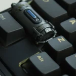 Close-up of a handcrafted Enriched Uranium Sample resin keycap, showcasing its rugged tactical design and post-apocalyptic radioactive glow from multiple angles.