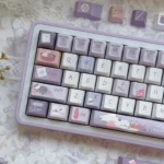 The Little Tailor Artistry PBT Tailor Keycap Set is displayed from multiple angles, showcasing its unique 'Little Tailor' motif, durable PBT texture.