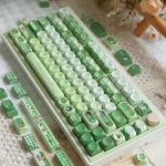 Whimsical Matcha Totoro PBT keycap set displayed from multiple angles, highlighting charming Totoro characters, soothing matcha green, and soft forest hues.