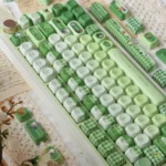 Angled view of the whimsical Matcha Totoro PBT keycap set, showcasing various charming Totoro characters in calming matcha green and soft forest hues.
