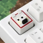 A charming, handcrafted pink pixelated Minecraft pig keycap made from vibrant resin, perfect as a playful keyboard accessory.