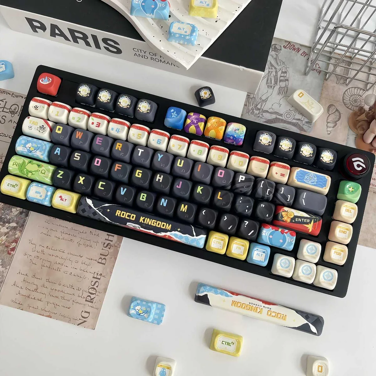 Close-up of the vibrant Roco Kingdom MOA PBT keycaps set, showcasing playful character designs and the exclusive dye-sub craftsmanship from multiple angles/