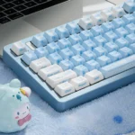 A collection of lustrous premium ceramic Cinnamoroll keycaps shown from various angles, highlighting the whimsical side-engraved art and soft vibrant color.