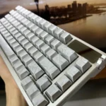 Angled view of ethereal silver keycaps, showcasing the luminous side-engraved characters and their sleek metallic finish.