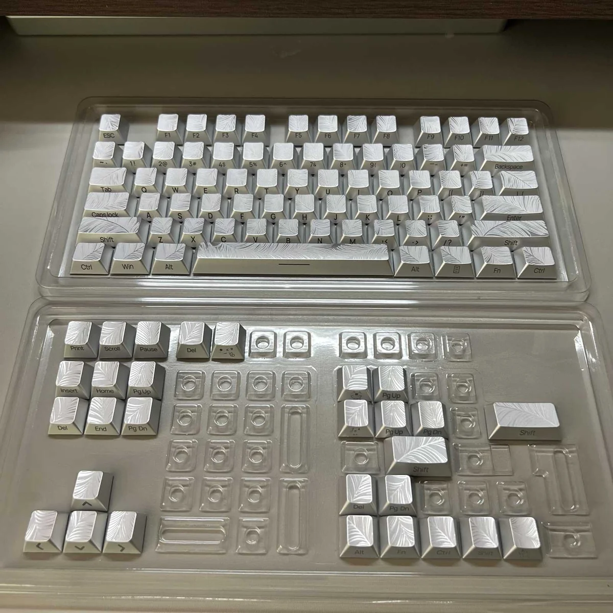 Detailed view of multiple ethereal silver Feather keycaps, showcasing their luminous side-engraved legends and sleek, metallic finish.