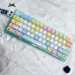 Vibrant Tamagotchi PBT keycaps shown from multiple angles, revealing their exclusive pixelated retro digital pet designs for a playful, nostalgic keyboard.