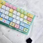 Exclusive Tamagotchi PBT keycaps from a unique angle, highlighting vibrant pixelated digital pet designs. This retro set creates a playful, nostalgic keyboard.