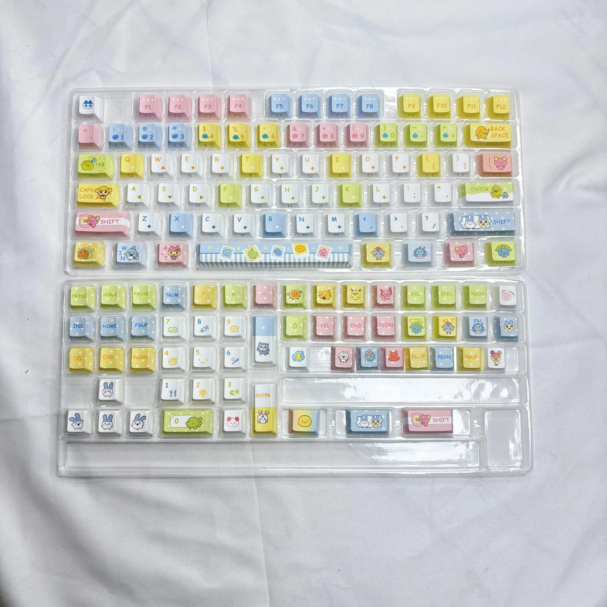 Vibrant 73-key Tamagotchi PBT keycap set, featuring retro pixelated digital pet designs for a cheerful, nostalgic desk setup.
