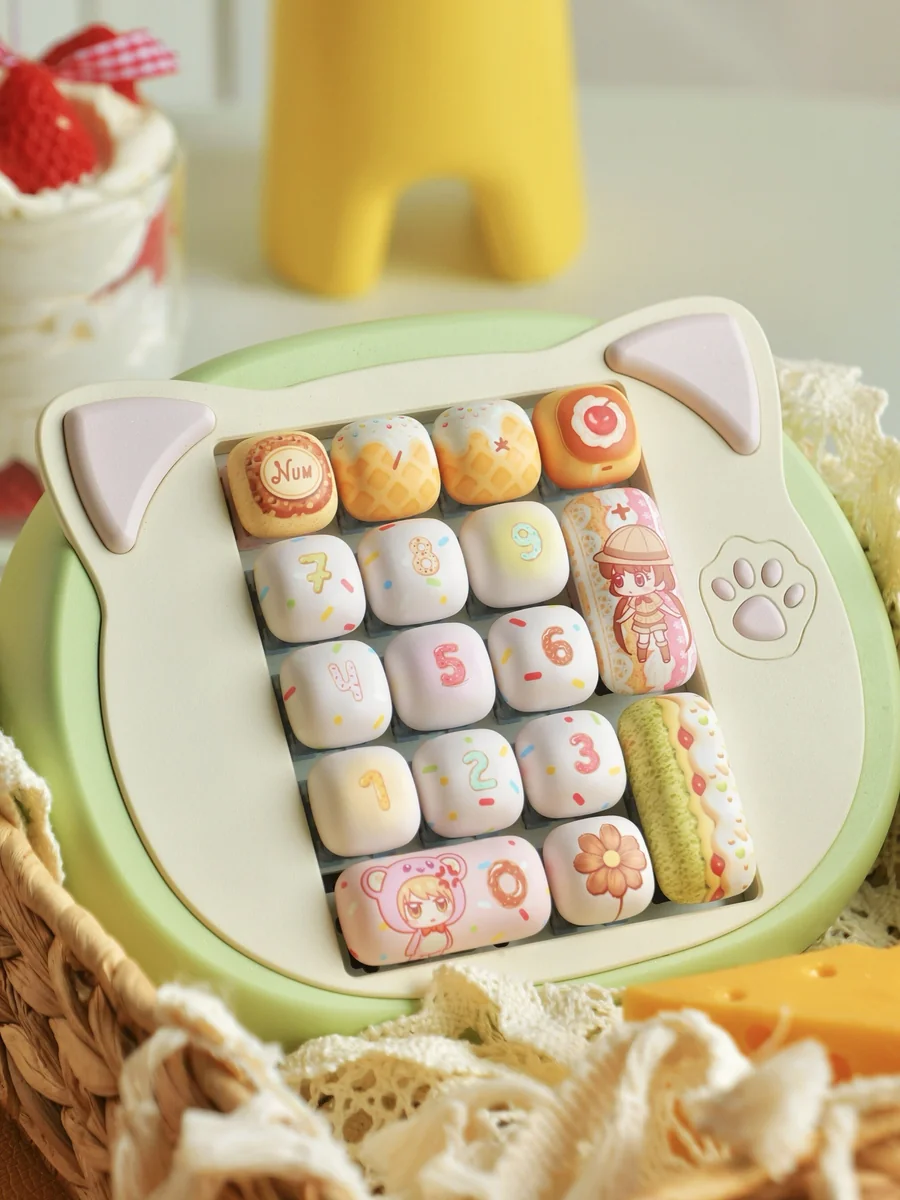 Close-up of the exclusive Yumeiro Patissiere PBT keycap set, showcasing playful anime characters and pastel dessert designs from a unique angle.