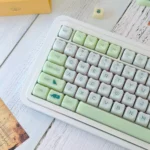 A close-up artistic view of the Jelly Green PC Keycap Set, showcasing its vibrant, smooth jade-like finish and nature-inspired MAO profile from various angles.