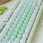 Sweet Nostalgia Dessert Keycap Set: Glossy PC keycaps in a lush gradient green, captured from a playful angle. Rounded, dessert-inspired, jelly-like.