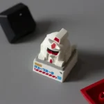 An artistic abstract backlit RX-78-2 Gundam artisan keycap, featuring its unique playful monkey face design and vibrant illumination from a distinct design.