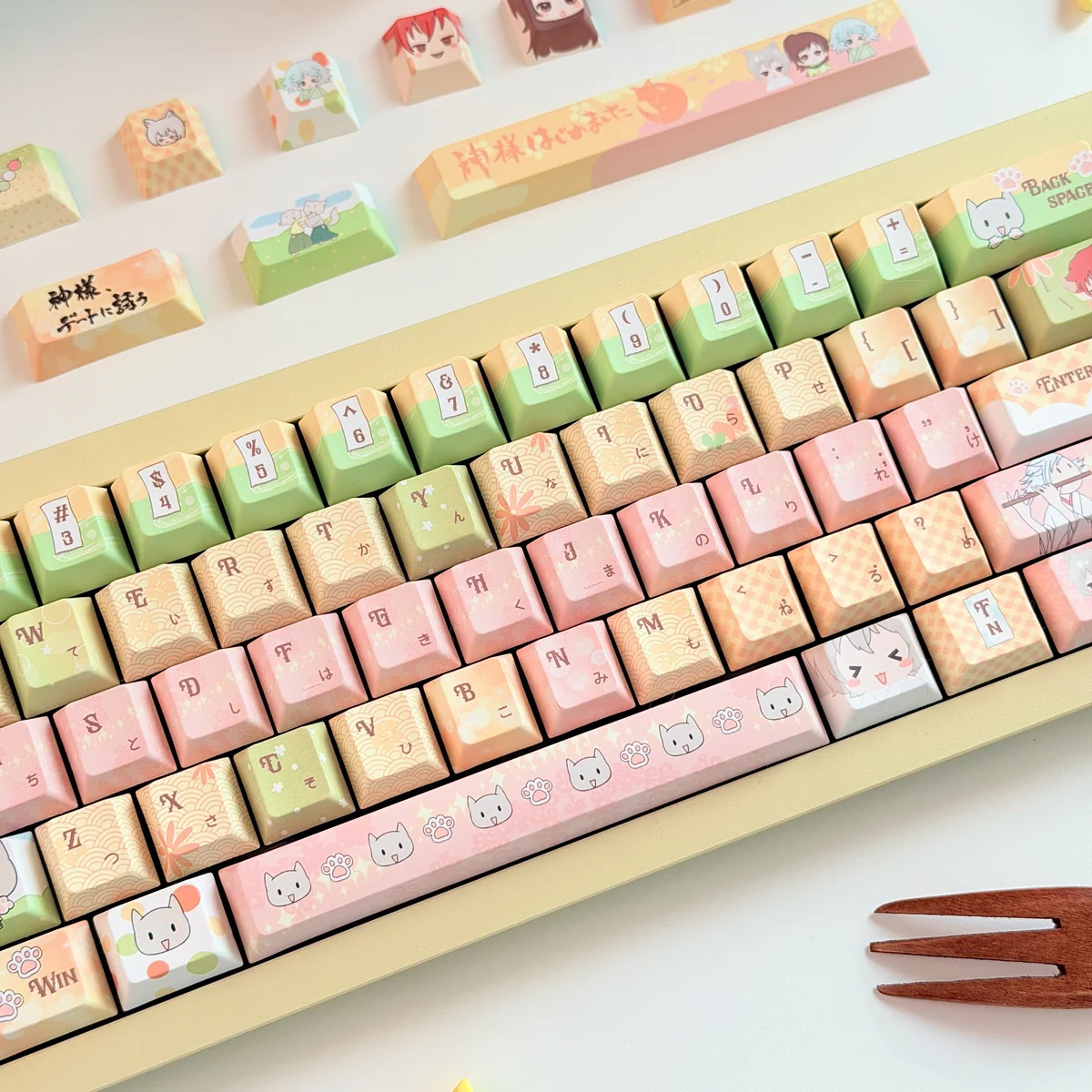 Close-up of the exclusive Kamisama Kiss anime PBT keycap set, showcasing multiple vibrant keycaps with charming character art from various angles.