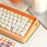 Close-up of playful Tangelo Mochi PBT dye-sub keycaps from multiple angles, showcasing their vibrant orange and cream colors and cute dessert theme.