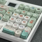Close-up of the whimsical zoo MOA keycap, showcasing its adorable rounded green animal design from various angles, a playful PBT accent for keyboards.