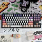 Hand-drawn graffiti keycaps on a black keyboard, featuring bold PBT keycaps with vibrant color blocking and playful street art icons.
