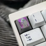 Close-up of the artisan hand-carved titanium Chainsaw Man Reze keycap, revealing its dynamic anime character design with vibrant metallic accents.