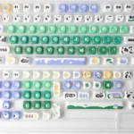 Cow pasture keycaps MOA PBT dye-sub set in a playful top-down layout with mint green keys, cream cows, milk icons, and meadow and sky accents.
