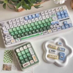 Cow Pasture keycaps MOA PBT dye-sub set with cream cows, green meadows, blue sky, and milk accents on a playful keyboard.