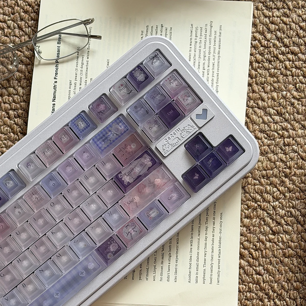 Frosted floral keycaps on a pastel purple and pink PC keyboard set with delicate floral illustrations in soft light.