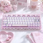 Pastel pink gloomy bear keycaps in PBT side-engraved translucent set on a white keyboard, styled with lace, hearts, and plush bear desk accessories.