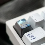 Hand-carved titanium Gojo Satoru keycap featuring monochrome portrait with vivid blue accents on dark titanium, shown mounted on a white keyboard.