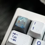 Close-up of hand-carved titanium Gojo Satoru keycap on a keyboard, showing a monochrome portrait with vivid blue accents.