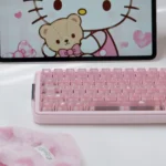Angled close-up of Frosted Pink Hello Kitty keycaps on a compact keyboard, highlighting the glossy candy-like PC finish and cute motifs.
