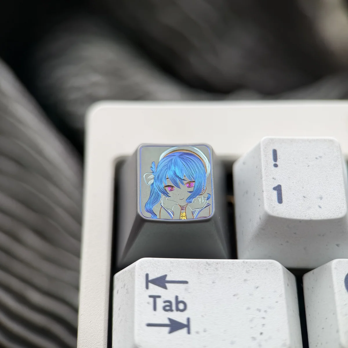 Hand-carved Hoshimachi Suisei titanium keycap from an artistic angle, revealing intricate lines and vibrant anime character details on premium alloy.