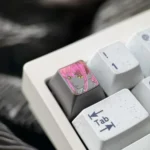 Artistic close-up of the hand-carved titanium Makima artisan keycap, revealing intricate Chainsaw Man line art and a dark metallic finish from a side angle.