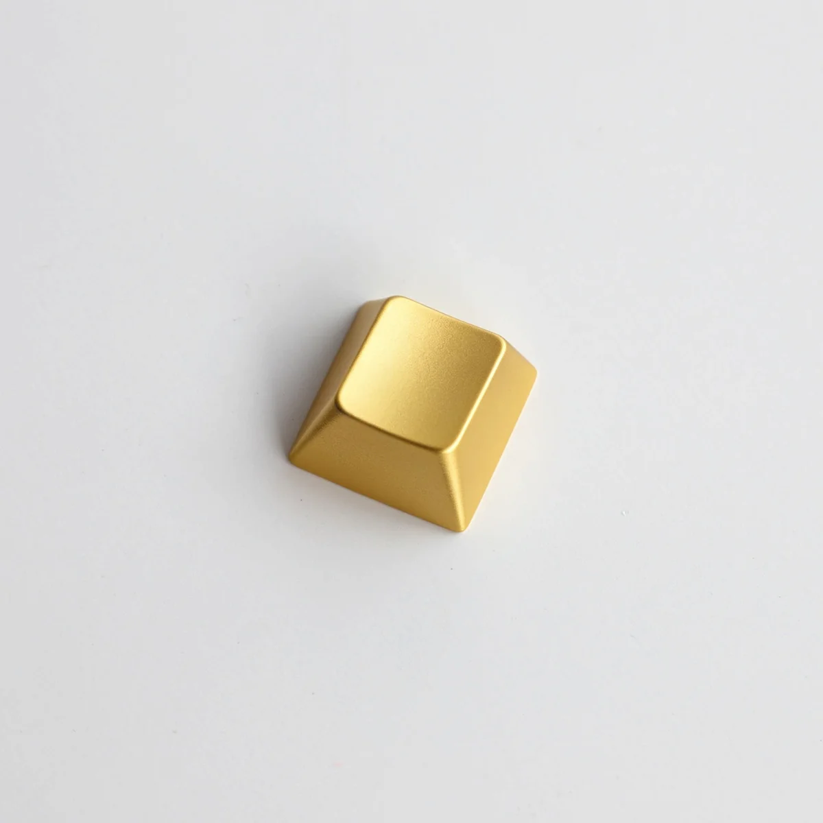 Close-up of a premium blank zinc alloy R1 directional metal keycap, showcasing its sleek, unadorned industrial-chic finish from various angles.