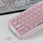 Frosted pink My Melody keycaps with cute bow and paw art sit on a pastel keyboard beside loose keys in close-up.