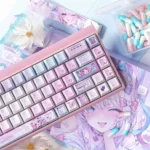 Exclusive Needy Streamer Overload 3.0 PBT keycap set, featuring vibrant KAngel anime art and an internet culture aesthetic with a pearlescent finish.