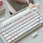 Pastel pink keycaps with gingham, bow, and heart details feature side-lit PBT and engraved legends for a dreamy romantic desk.