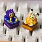 Playful ultra-detailed 3D Pokemon artisan keycaps showing dessert-themed Cosplay Pikachu wearing Gengar and Mimikyu hoods on cake bases.