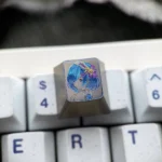 Vibrant Re:Zero Rem hand-carved titanium artisan keycap, showcasing intricate details and colorful lines from a unique angle, highlighting its artistry.