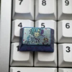 Violet-blue anodized Rem titanium keycap with pastel anime maid portrait and floral accents, installed on a white keyboard.
