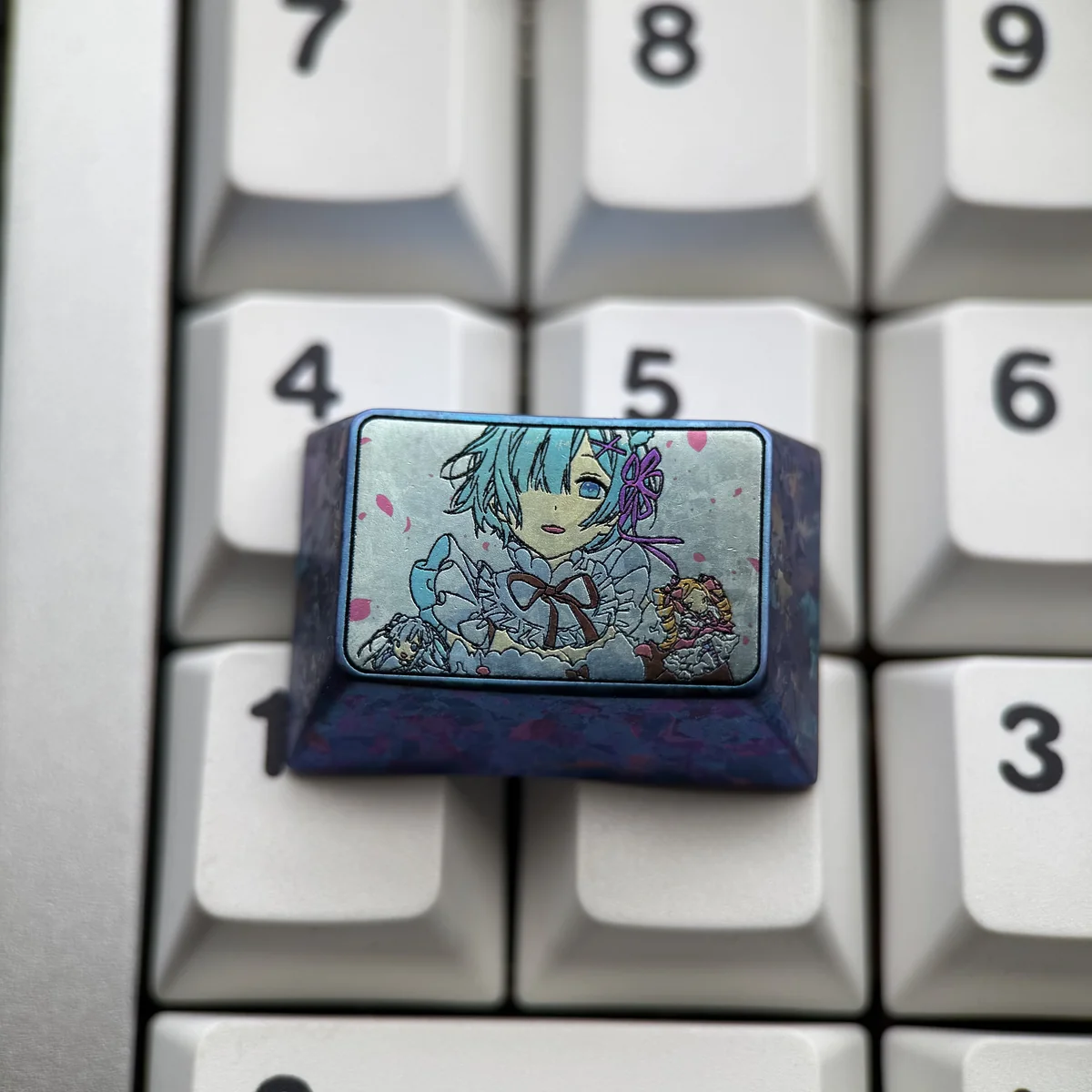 Violet-blue anodized Rem titanium keycap with pastel anime maid portrait and floral accents, installed on a white keyboard.