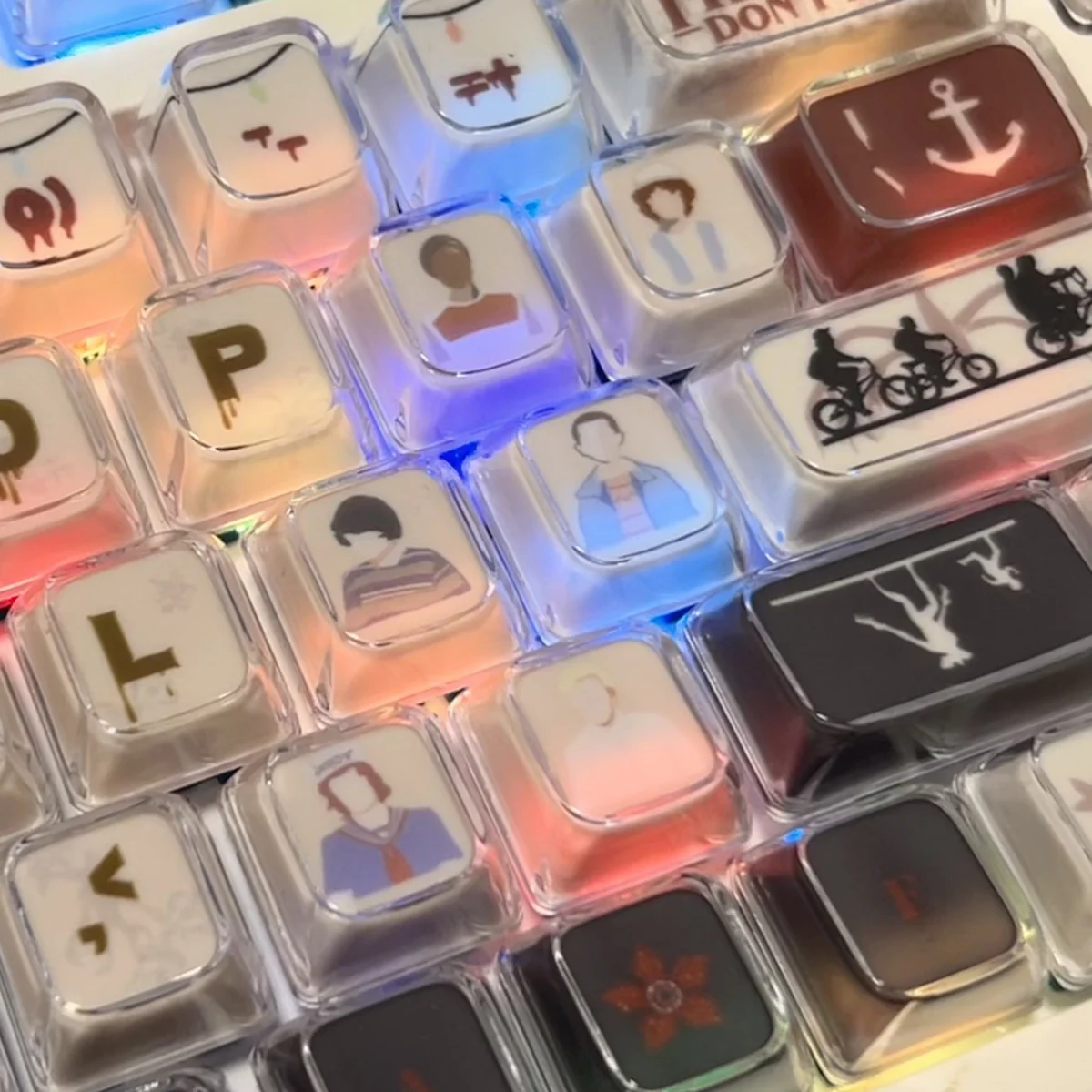 Multiple views of the iconic Stranger Things Amber Pudding PBT keycap set, highlighting the translucent Hawkins Glow and retro 80s aesthetic with playful design.